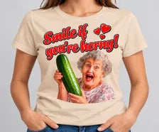 T-shirt bege Smile If You're Horny com frase vermelha e senhora a segurar um pepino.